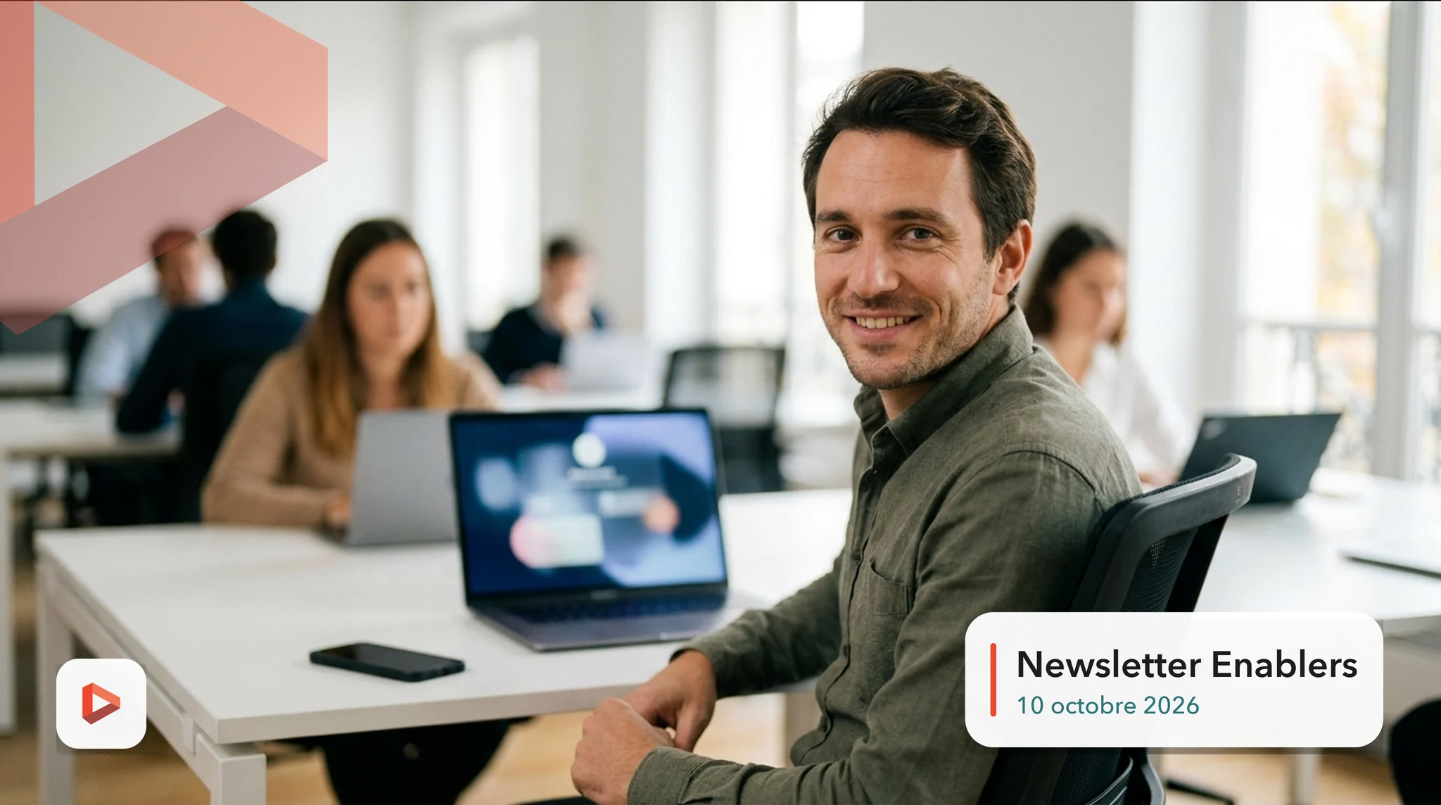 Directeur marketing souriant à son bureau dans un open space lumineux, smartphone posé à côté de son ordinateur, newsletter Enablers du 10 octobre 2026